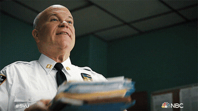 A Man In A Police Uniform Is Holding A Stack Of Papers In His Hand GIF