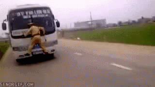 A Man In A Police Uniform Is Pushing A Bus Down A Road . GIF