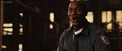 A Man In A Police Uniform Is Standing In A Dark Room Holding His Fist Up . GIF