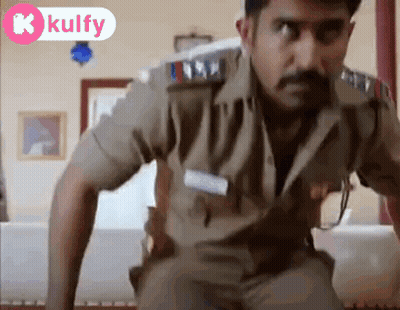 A Man In A Police Uniform Is Standing In A Living Room Looking At The Camera . GIF