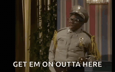 A Man In A Police Uniform Is Standing In A Room With The Words `` Get Em On Outta Here '' Written On The Screen . GIF