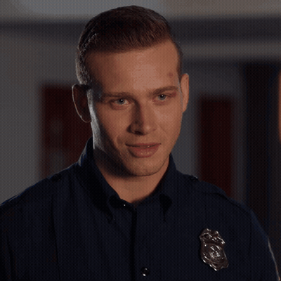 A Man In A Police Uniform Is Standing In Front Of A Box GIF