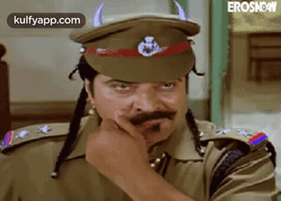 A Man In A Police Uniform Is Wearing A Hat With Horns On It And A Mustache . GIF