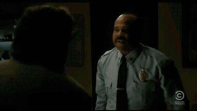 A Man In A Police Uniform Says " I 'Ll Take It " In A Dark Room GIF