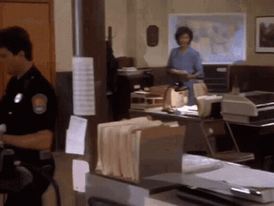 A Man In A Police Uniform Stands In A Police Station GIF