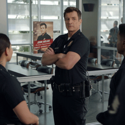 A Man In A Police Uniform Stands In Front Of A Poster That Says John Nolan GIF