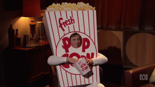A Man In A Popcorn Costume Holds A Bag Of Popcorn In Front Of His Face GIF