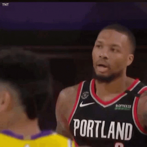 A Man In A Portland Jersey Is Talking To Another Man In A Yellow Shirt . GIF