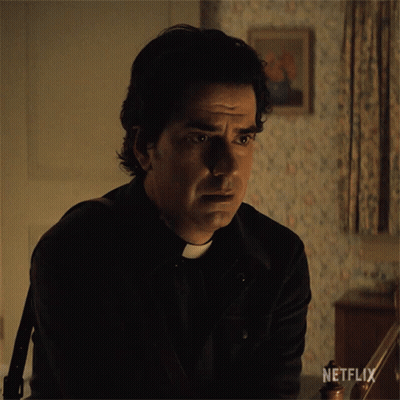 A Man In A Priest 'S Outfit Is Sitting In A Dark Room With A Netflix Logo On The Bottom Right GIF