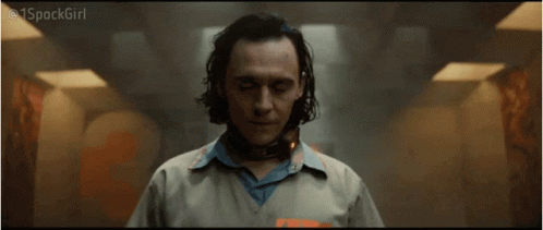 A Man In A Prison Uniform With A Collar Around His Neck Is Standing In A Hallway . GIF