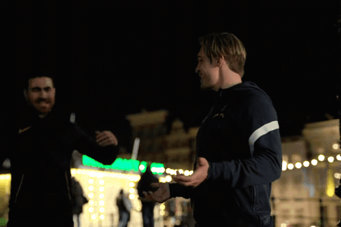 A Man In A Puma Jacket Shakes Hands With Another Man In A Black Jacket GIF