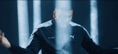 A Man In A Puma Jacket Stands In Front Of A Blue Light GIF