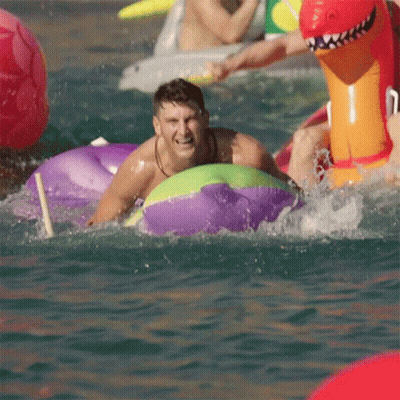 A Man In A Purple And Green Raft Is Splashing In The Water GIF