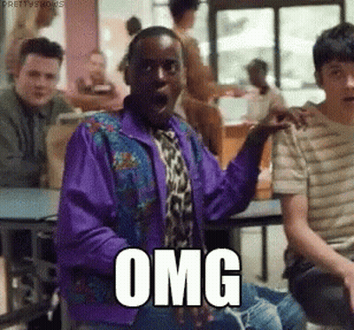 A Man In A Purple Jacket And Tie Is Sitting At A Table With Other People And Making A Surprised Face . GIF