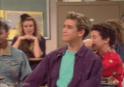 A Man In A Purple Jacket Is Sitting In A Classroom With Other Students GIF