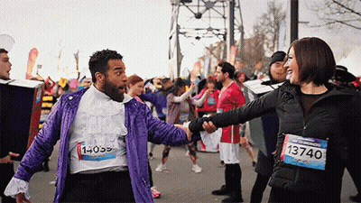 A Man In A Purple Jacket With The Number 1 On His Shirt Shakes Hands With A Woman GIF