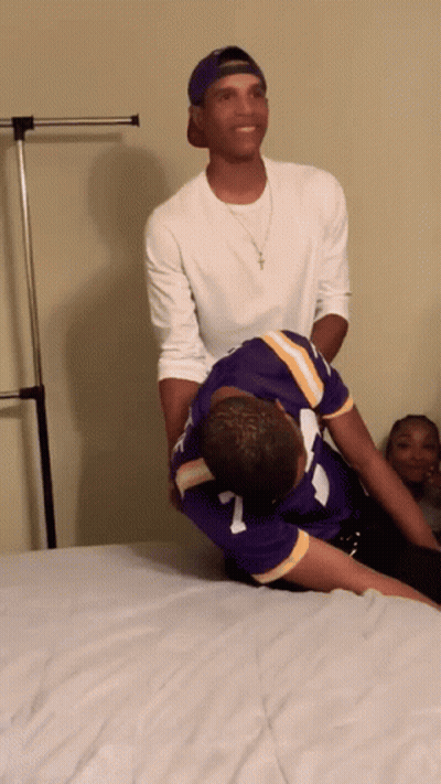 A Man In A Purple Jersey With The Number 7 On It Is Laying On Another Man 'S Back GIF
