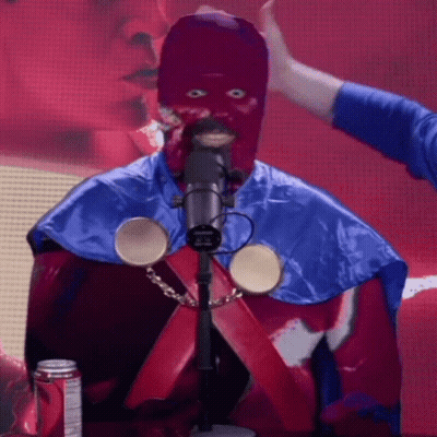 A Man In A Purple Mask Is Standing In Front Of A Microphone With A Can Of Dr Pepper In The Background GIF