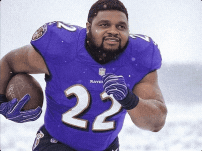 A Man In A Purple Ravens Jersey Holds A Football GIF