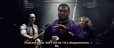 A Man In A Purple Robe Is Holding A Hammer And Talking To A Group Of People In A Dark Room . GIF