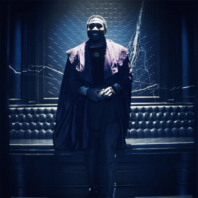 A Man In A Purple Robe Stands In Front Of A Blue Wall GIF