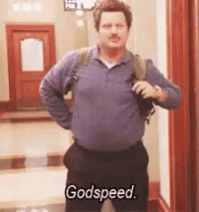 A Man In A Purple Shirt And Black Pants Is Standing In A Hallway And Says `` Godspeed '' . GIF