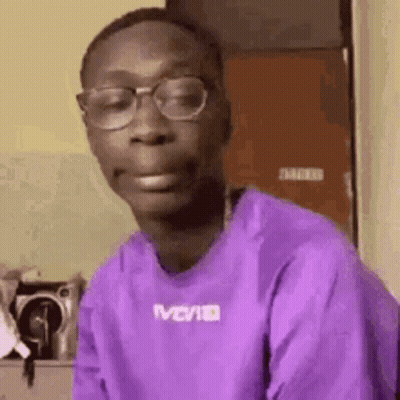 A Man In A Purple Shirt And Glasses Is Making A Funny Face . GIF