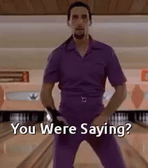 A Man In A Purple Shirt And Pants Is Standing On A Bowling Alley And Says `` You Were Saying '' . GIF