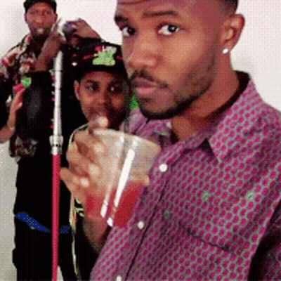A Man In A Purple Shirt Holds A Cup Of Red Liquid GIF