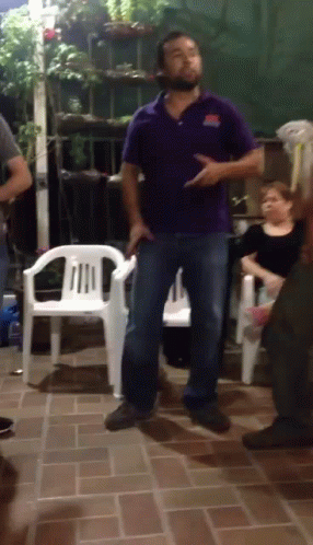 A Man In A Purple Shirt Is Dancing In A Room GIF