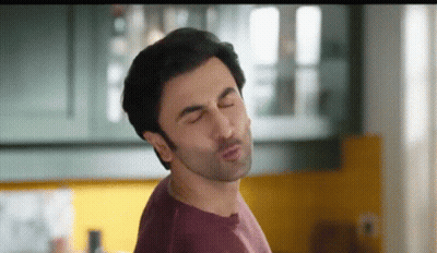 A Man In A Purple Shirt Is Making A Funny Face With His Eyes Closed . GIF