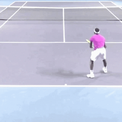 A Man In A Purple Shirt Is Playing Tennis On A Court GIF