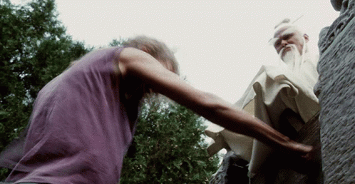 A Man In A Purple Shirt Is Reaching Out To Another Man GIF