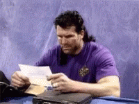 A Man In A Purple Shirt Is Reading A Letter . GIF