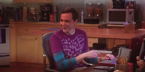 A Man In A Purple Shirt Is Sitting In A Chair In Front Of A Computer . GIF