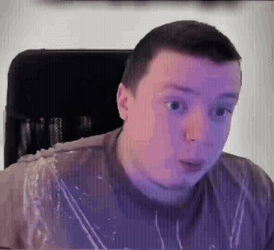 A Man In A Purple Shirt Is Sitting In A Chair With A Surprised Look On His Face . GIF