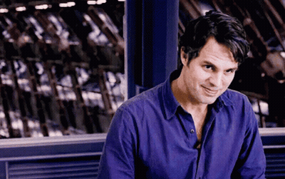 A Man In A Purple Shirt Is Sitting In Front Of A Window . GIF