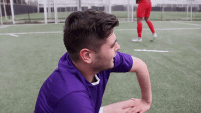 A Man In A Purple Shirt Is Sitting On The Field GIF