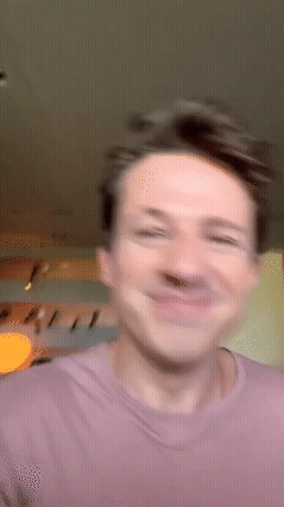 A Man In A Purple Shirt Is Smiling And Making A Funny Face GIF