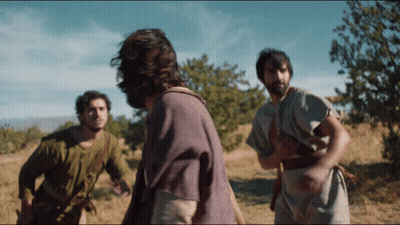 A Man In A Purple Shirt Is Standing In A Field With Other Men GIF