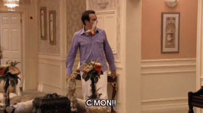 A Man In A Purple Shirt Is Standing In A Hallway And Says " C Mon " GIF