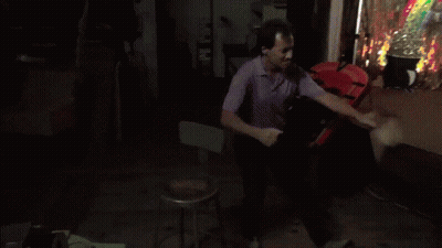 A Man In A Purple Shirt Is Standing In Front Of A Clown Costume GIF