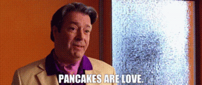 A Man In A Purple Shirt Is Standing In Front Of A Window And Says Pancakes Are Love . GIF