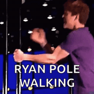 A Man In A Purple Shirt Is Standing On A Pole With His Hands In The Air . GIF