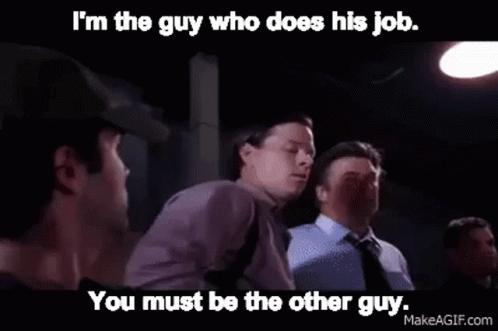 A Man In A Purple Shirt Is Talking To Another Man In A Dark Room . GIF