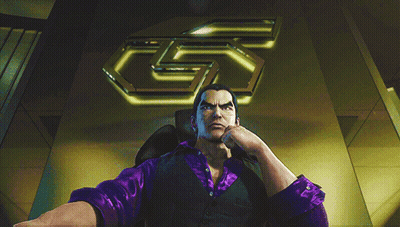 A Man In A Purple Shirt Sits In A Chair In Front Of A Large 5 GIF