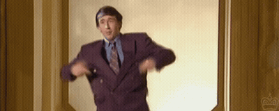 A Man In A Purple Suit And Tie Is Standing In A Doorway And Dancing . GIF