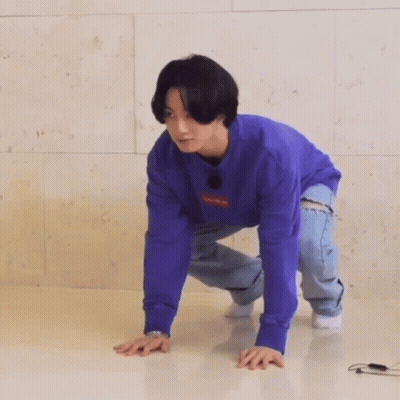 A Man In A Purple Sweater And Jeans Is Crawling On The Floor . GIF