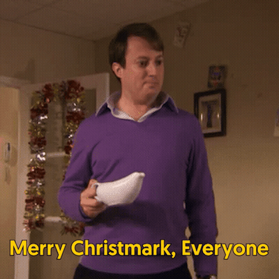 A Man In A Purple Sweater Is Holding A White Object And Says Merry Christmark Everyone GIF