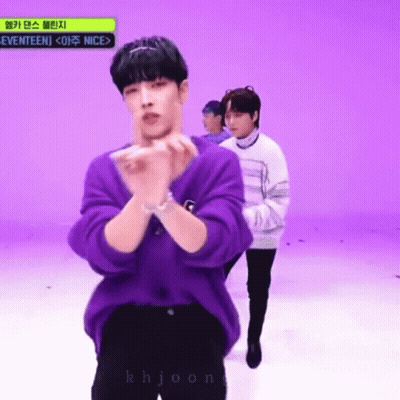 A Man In A Purple Sweater Is Standing In Front Of A Purple Wall . GIF